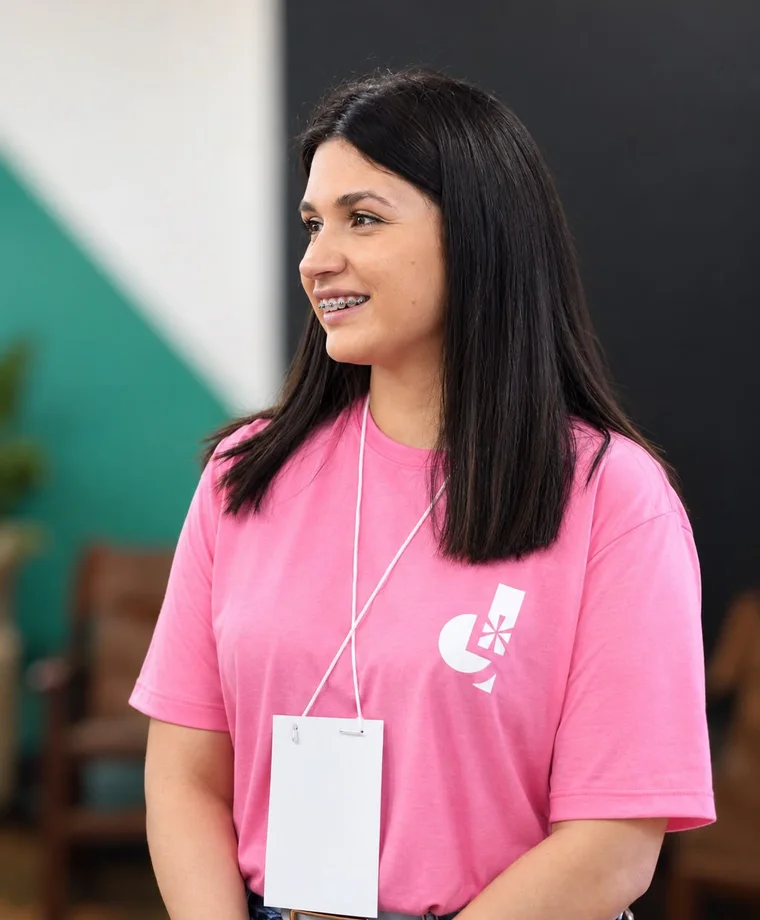 Foto de Geise sorrindo no Unoesc Day, de camiseta rosa e crachá.