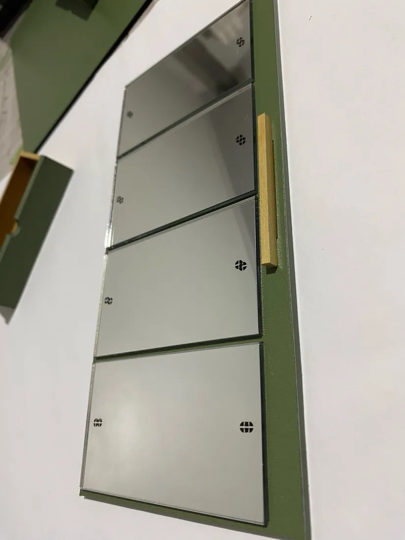 Porta da maquete com quatro placas de espelho e um puxador de madeira.
